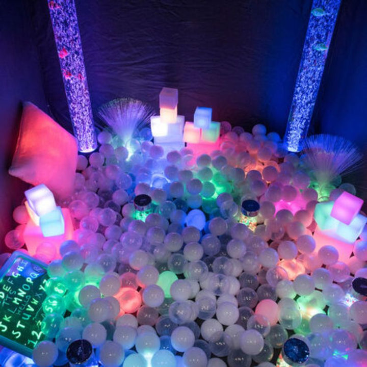 Interior of the TTS Pop-Up Sensory Space set up with bubble tubes, light-up cubes and a glowing ball pit, creating a complete portable sensory room