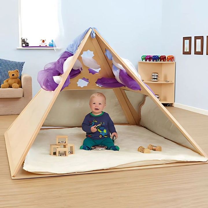 Toddler boy playing inside the TTS Wooden Pyramid Den, an early years wooden den designed for calm corners, imaginative play, and sensory learning