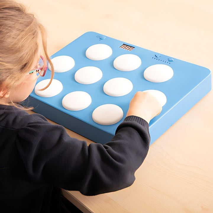 Child pressing an illuminated button on the TTS Portable Light Up Reaction Wall Game, building hand-eye coordination, reaction speed, and gross motor skills through active sensory play
