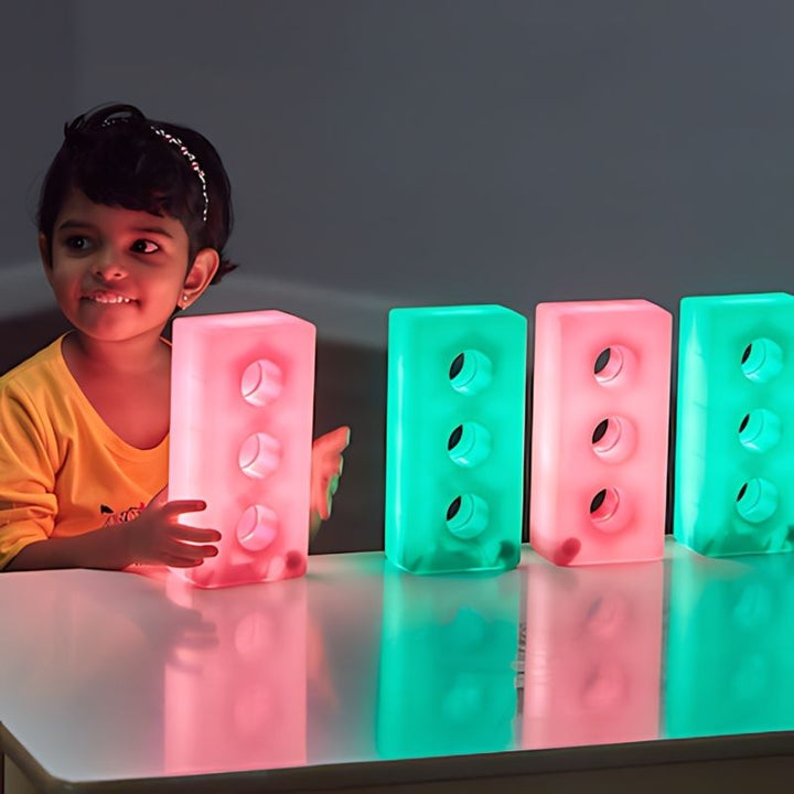 Child aligning TTS Light Up Glow Construction Bricks in a row during cause and effect sensory play in a classroom or therapy setting