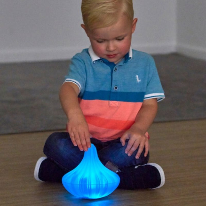 Toddler using both hands to explore a glowing blue TTS Light Up Spinning Top, supporting fine motor skill development and sensory curiosity from 10 months and up