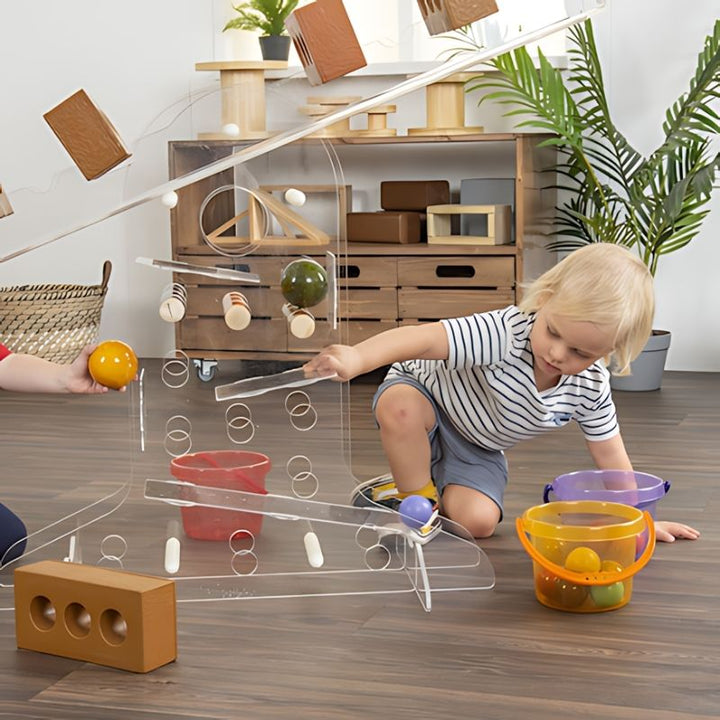 Child in a striped top exploring the TTS STEAM Discovery Centre's ramp track and balance structure during early learning play