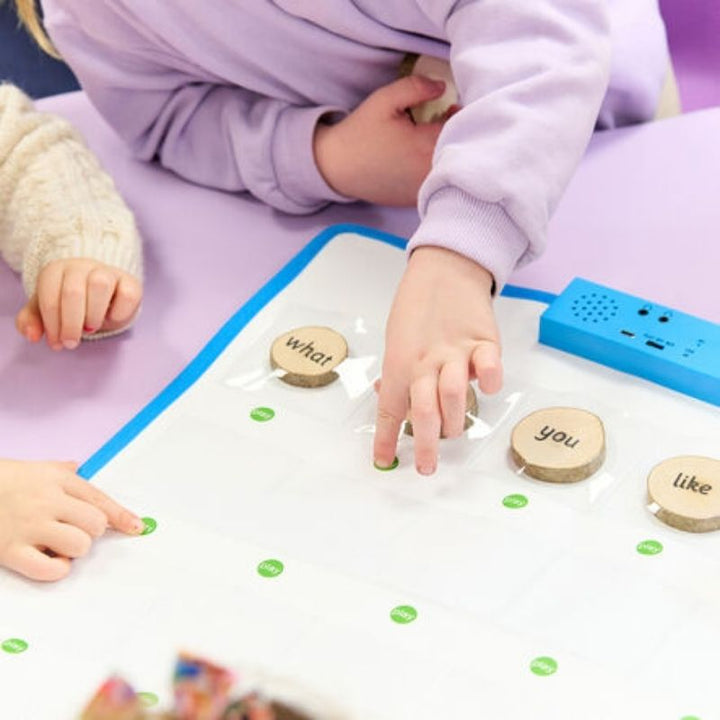 Two children placing wooden word tokens on the TTS Interactive Talking Mat during a spoken language activity, using the recordable pockets for interactive vocabulary learning
