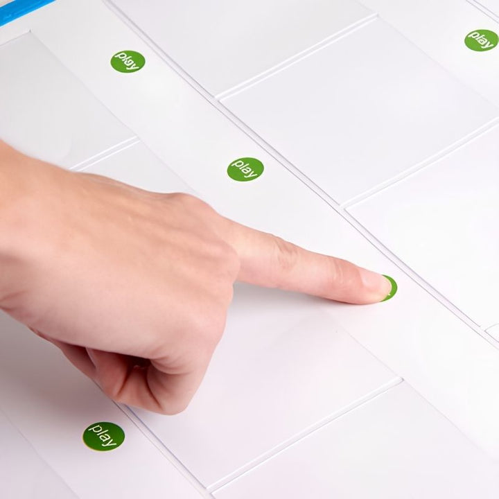 Close-up of a finger pressing a green play button on the TTS Interactive Talking Mat, demonstrating the simple one-touch recording and playback interaction