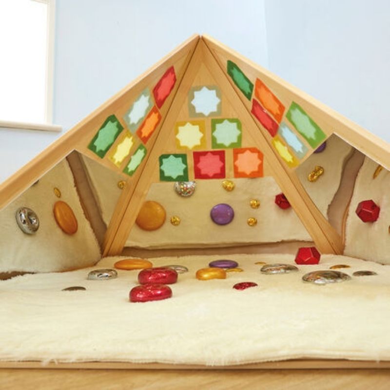 Full view of the TTS Learning Location Wooden Pyramid Den showing beech and plywood construction, three mirrored sides, and cut-out shapes for sensory exploration