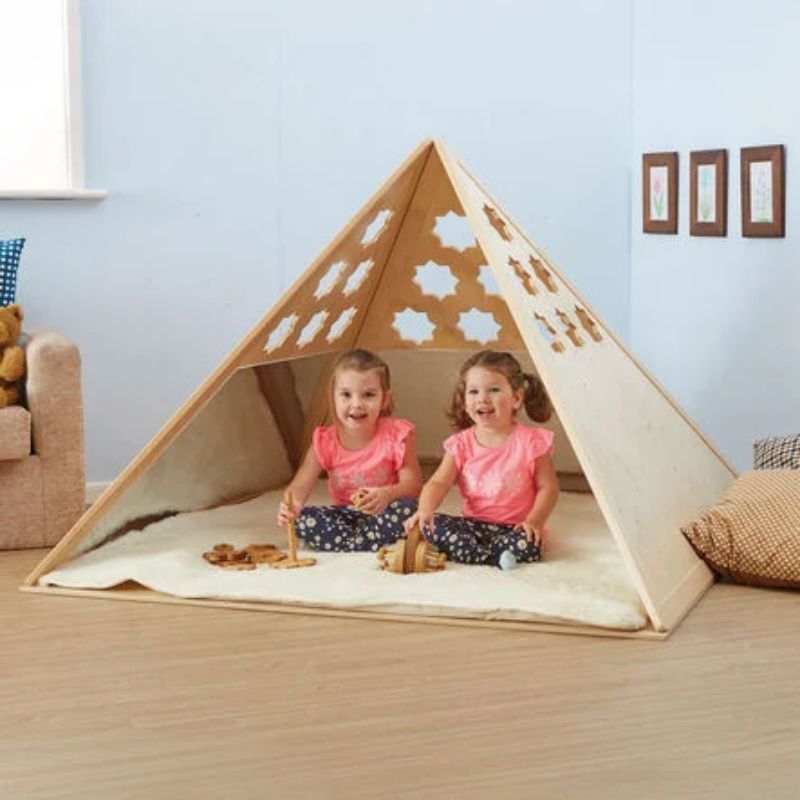 Front view of two girls sitting inside the TTS Learning Location Wooden Pyramid Den, showing the open-access entry and roomy interior for two to three children
