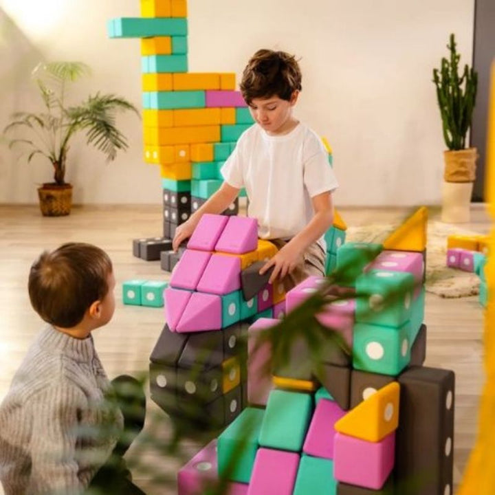 Boys actively playing and riding a structure built from TUKI Big Magnetic Foam Blocks Smart 280, showing the strength and stability of large-format magnetic foam construction