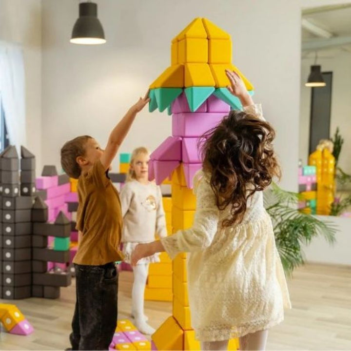 Three children building floor-scale structures simultaneously with the TUKI BIG Smart Magnetic Blocks Smart 160, demonstrating the sub-group construction dynamic that 160 large-format magnetic foam blocks enables within a 9-12 child group session