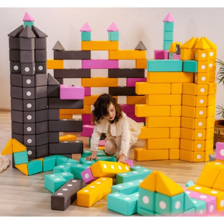Child building a landscape-scale floor structure with the TUKI BIG Smart Magnetic Blocks Smart 75, demonstrating the large-format 10cm SMART shape construction the 75-piece pyramid group set enables