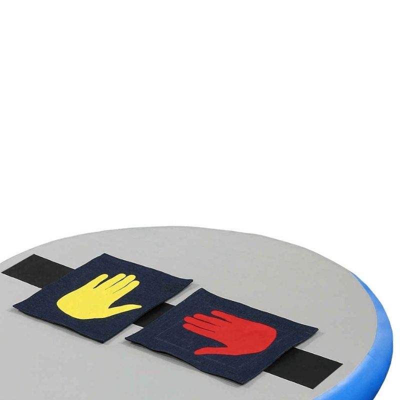 Top view of the Tumbl Trak Hot Spot showing yellow and red Velcro Hands and Feet attached to the 4-inch loop Velcro line on the surface, demonstrating the compatible teaching accessories for hand and foot placement guidance in gymnastics and cheer skill training