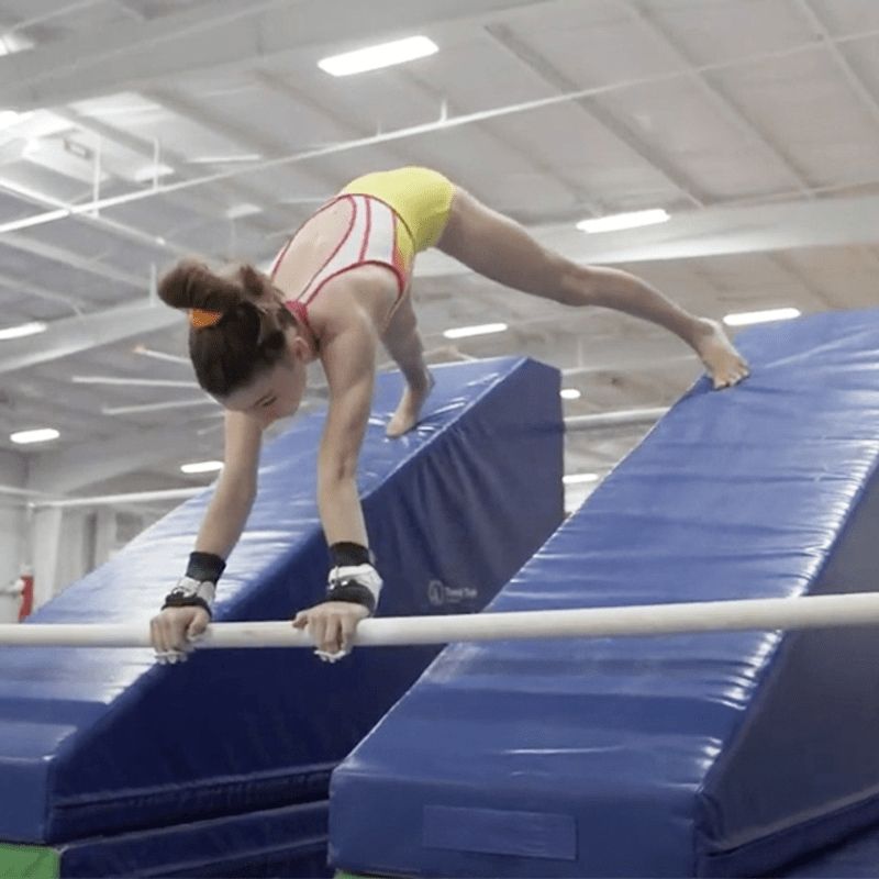 Girl actively balancing or practising a gymnastics skill on the Tumbl Trak Smart Wedge, demonstrating the inclined wedge configuration used for beam progressions, body shaping, and spatial awareness development