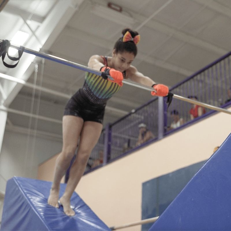 Girl performing a gymnastics skill or balance progression on the Tumbl Trak Smart Wedge, showing the three-angle dense foam block in active use for skill development in a gymnastics club or training setting
