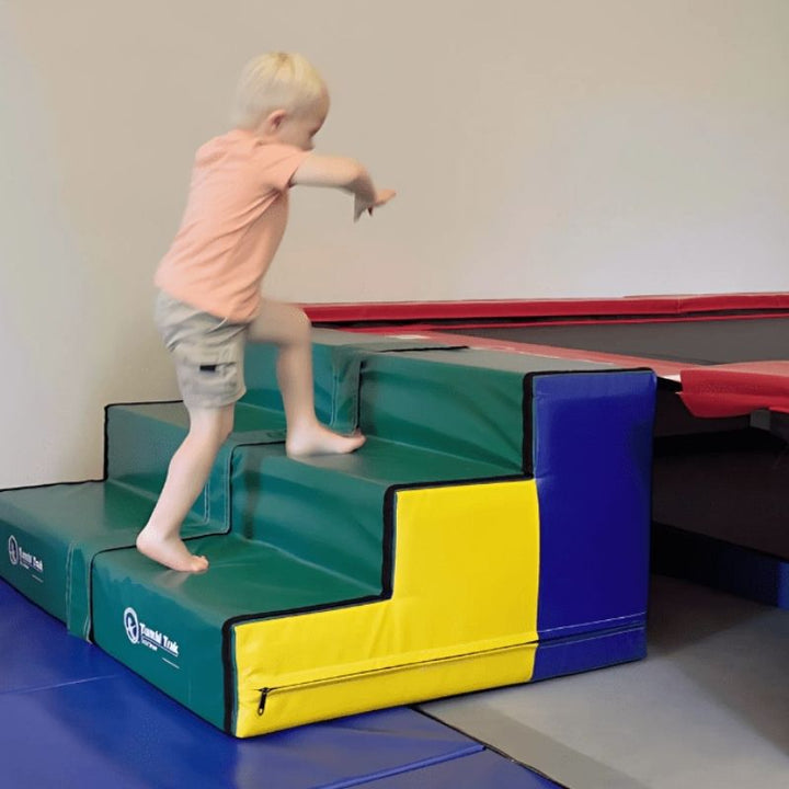 Boy using the Tumbl Trak Steps in an active play and training context, showing the stable firm foam construction and safe three-step access design for gymnastics clubs, school PE, and home movement spaces