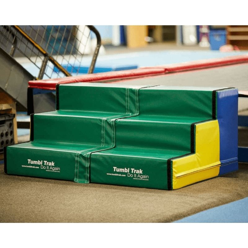 Two Tumbl Trak Steps sets positioned in an indoor gymnastics gym setting, demonstrating the side-by-side Velcro connection for full-width Tumbl Trak access in a club or school PE environment
