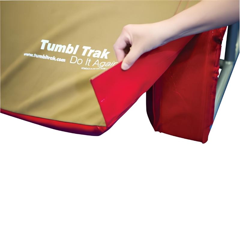 Close-up of the Tumbl Trak T-Trainer Cover PRO being attached by Velcro to the training frame, showing the simple removable suede cover installation that gives the vault trainer the feel of a traditional competition vault table