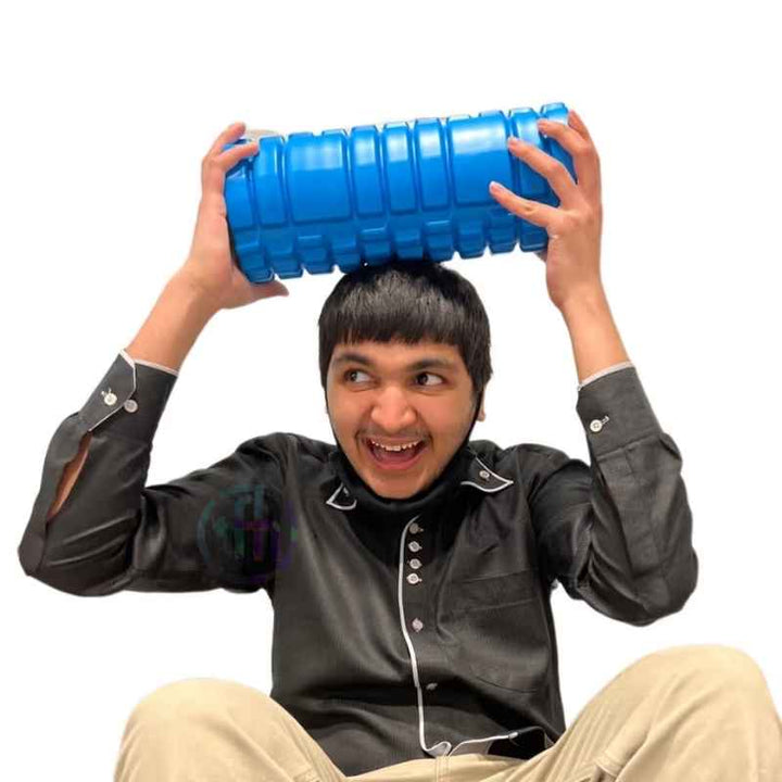 Young man playfully holding the TFH Big Texture Vibrating Roller overhead, showing the textured surface of this vibrating sensory roller