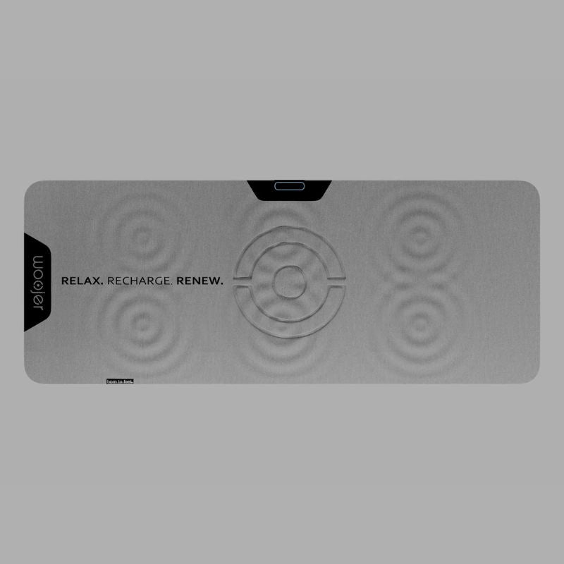 Woojer MAT vibroacoustic mat shown from above, with ripple markings across its haptic zones and a center control area on a gray vibrating mat