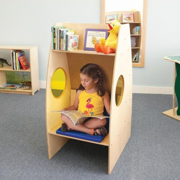 Child reading inside the Whitney Brothers Alone Zone private reading chair, showing the enclosed structure, yellow acrylic side windows, and cosy interior of the classroom quiet space chair