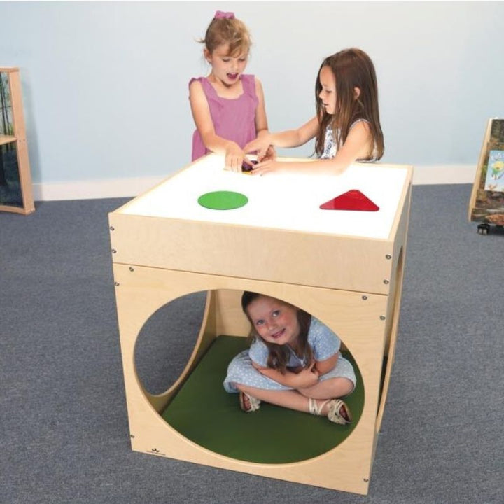 Three children playing with the Whitney Brothers Superbright LED Creative Cube and Mat Bundle, showing kids using the light table surface and the cube's tunnel openings in a classroom setting