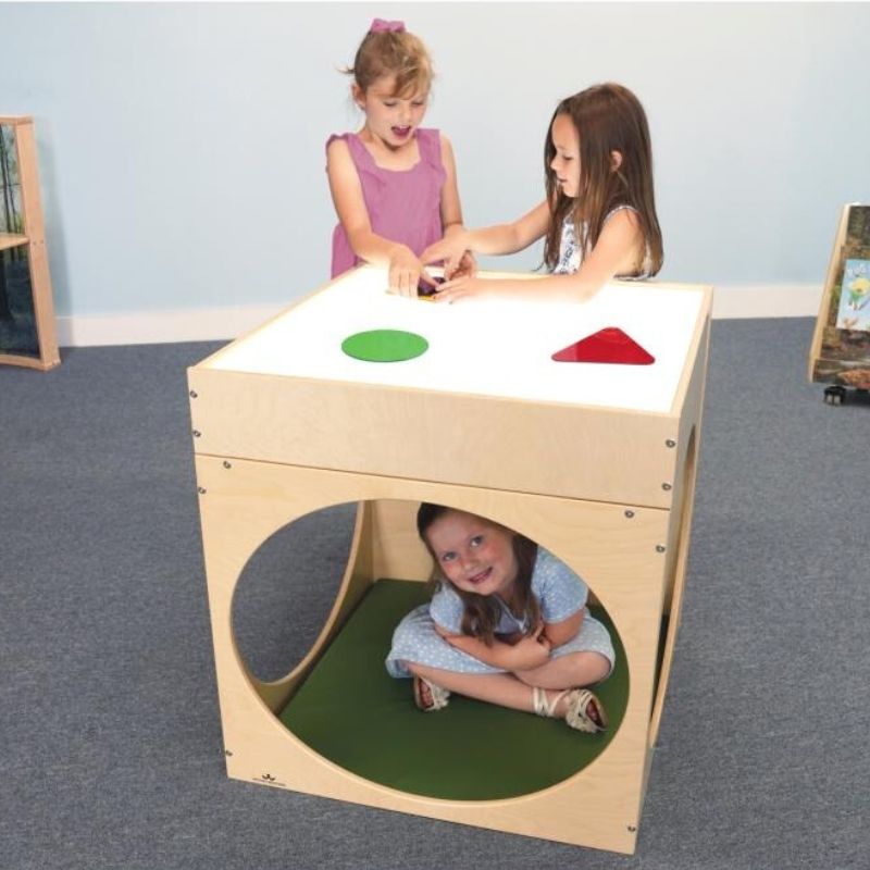 Three children playing with the Whitney Brothers Superbright LED Creative Cube and Mat Bundle, showing kids using the light table surface and the cube's tunnel openings in a classroom setting