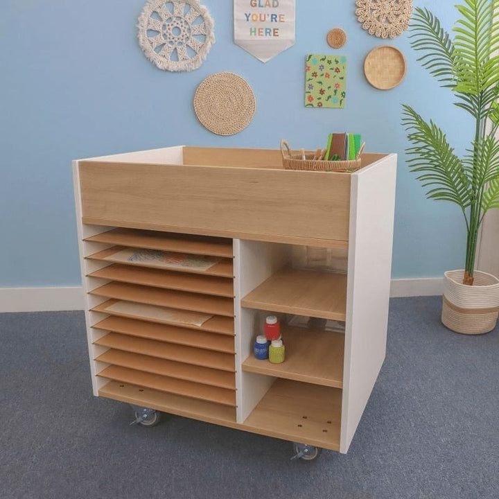 Whitney Brothers elevatED Art Supply Cart in a classroom setting, showing the full 33" wide two-tone mobile art storage cart with heavy-duty lockable casters and art supplies stored in multiple sections