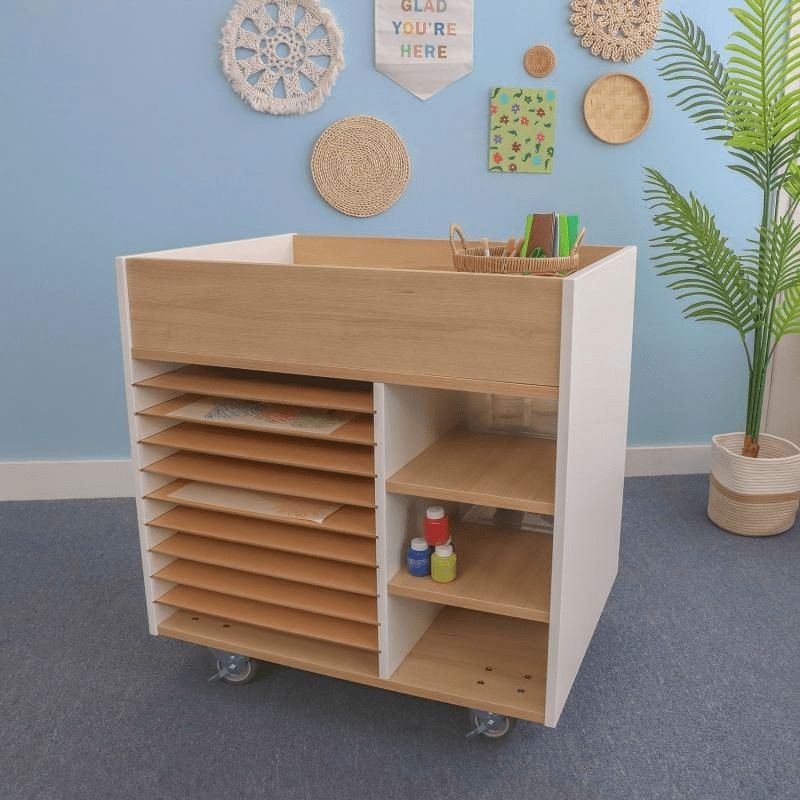 Whitney Brothers elevatED Art Supply Cart in a classroom setting, showing the full 33" wide two-tone mobile art storage cart with heavy-duty lockable casters and art supplies stored in multiple sections