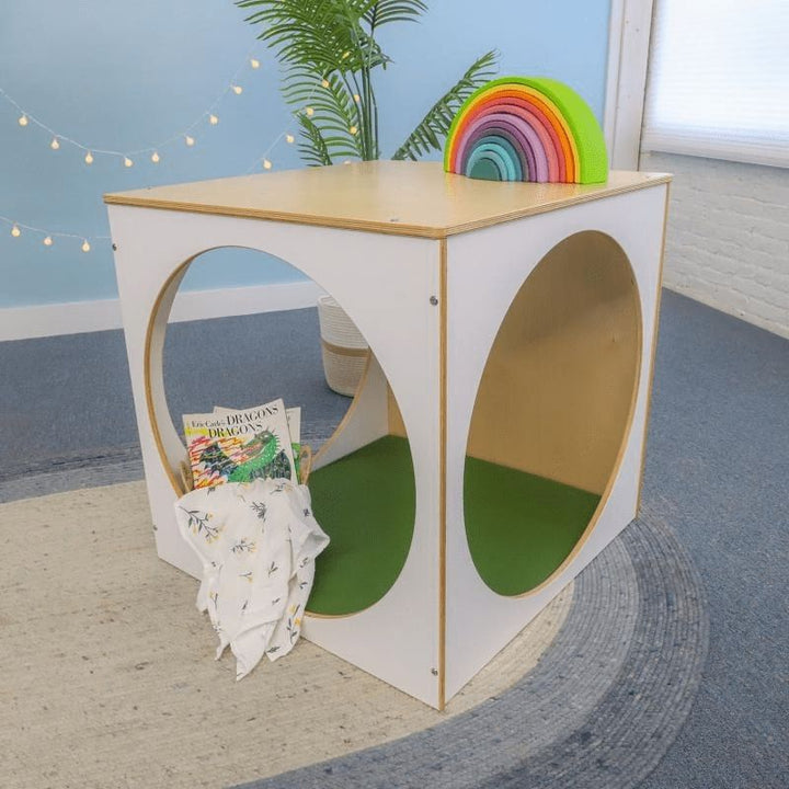 Side view of the Whitney Brothers elevatED Play House Cube with Floor Mat in a classroom setting, showing the 25-inch circular openings for supervision visibility and child entry