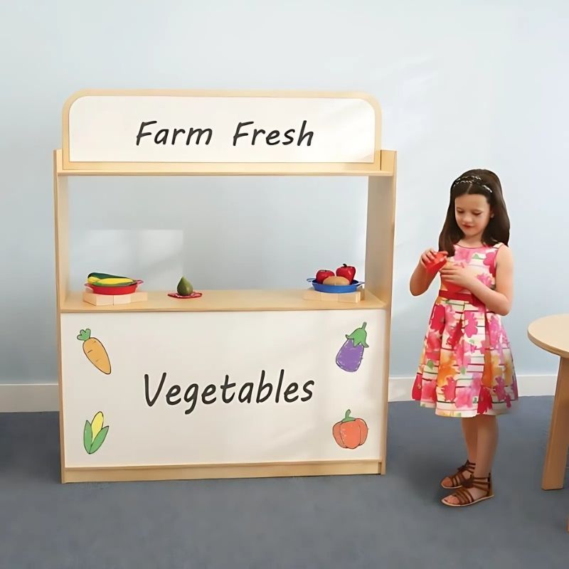 Children engaged in dramatic play with the Whitney Brothers Imagination Station, showing the storefront/puppet theatre configuration with dry erase boards and the 24" stage opening