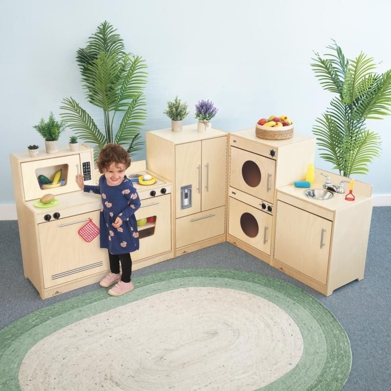 Child engaged in dramatic kitchen play with the Whitney Brothers Contemporary Kitchen Ensemble Natural, showing the five-piece birch plywood play kitchen set in a classroom setting