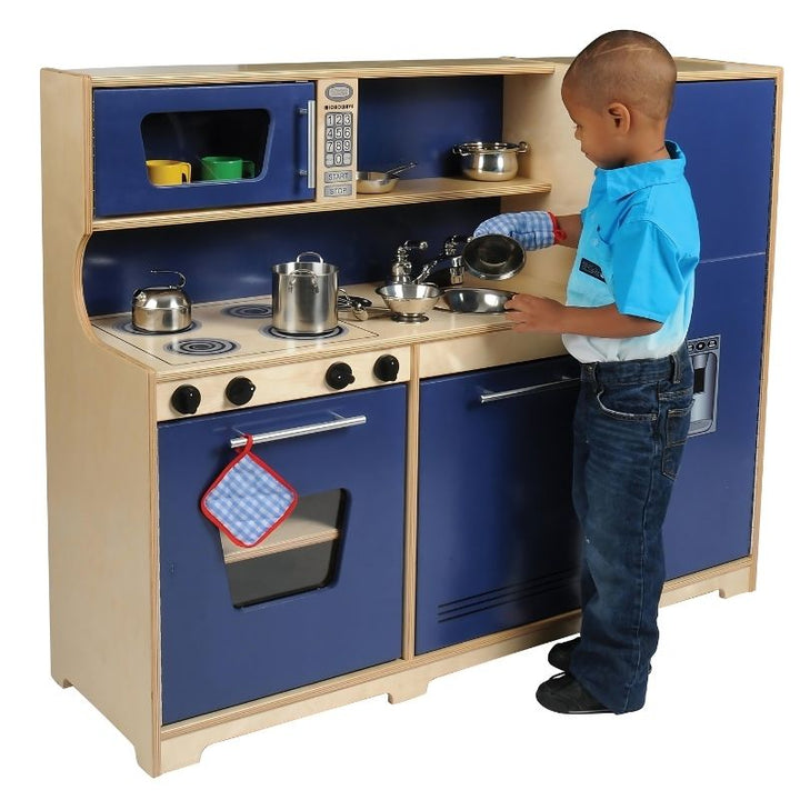 Child actively playing with the Whitney Brothers Monaco Kitchen 3-Piece Playset, a wooden dramatic play kitchen for classrooms and home