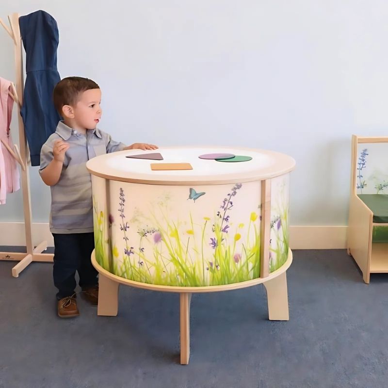 Child playing at the Whitney Brothers Nature View Radiant LED Light Table, showing the round cylinder design with no corners and the illuminated nature scene side panels