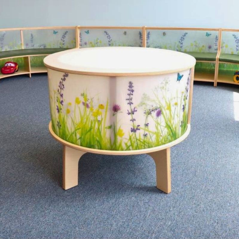 Portrait view of the Whitney Brothers Nature View Radiant LED Light Table showing the full cylinder form with the illuminated Nature View side panels glowing and the birch plywood leg construction
