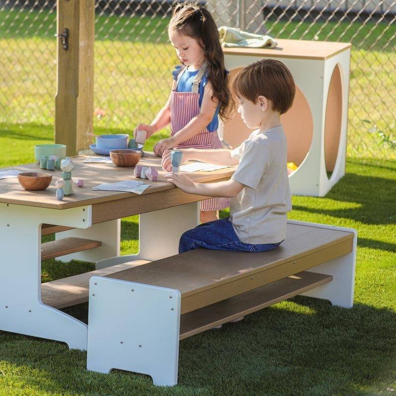 Two children using the Whitney Brothers outdoorED outdoor classroom bench, showing child-scaled 12-inch seat height and dual-sided storage shelf accessibility
