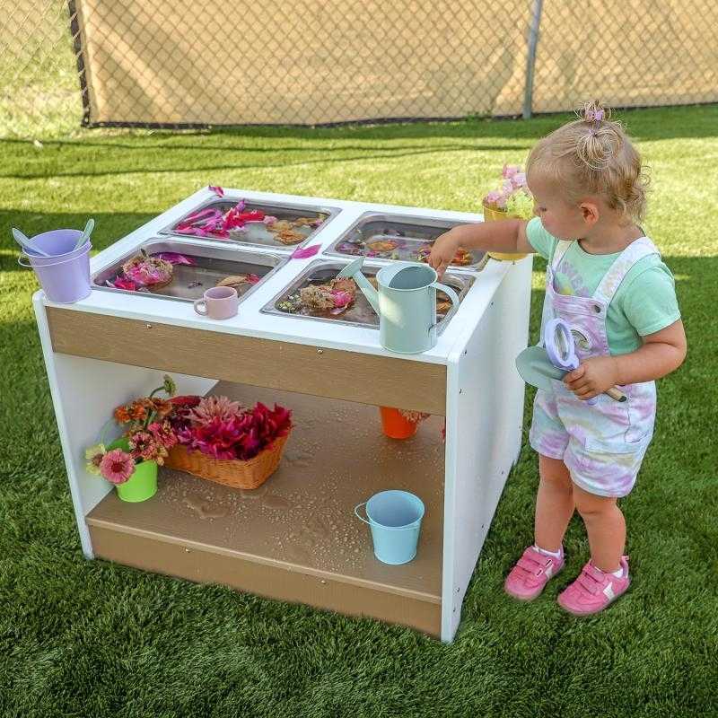 Landscape view of child engaged in outdoor sensory play at the Whitney Brothers outdoorED Sensory Table, showing full weatherproof HDPE profile in outdoor classroom setting