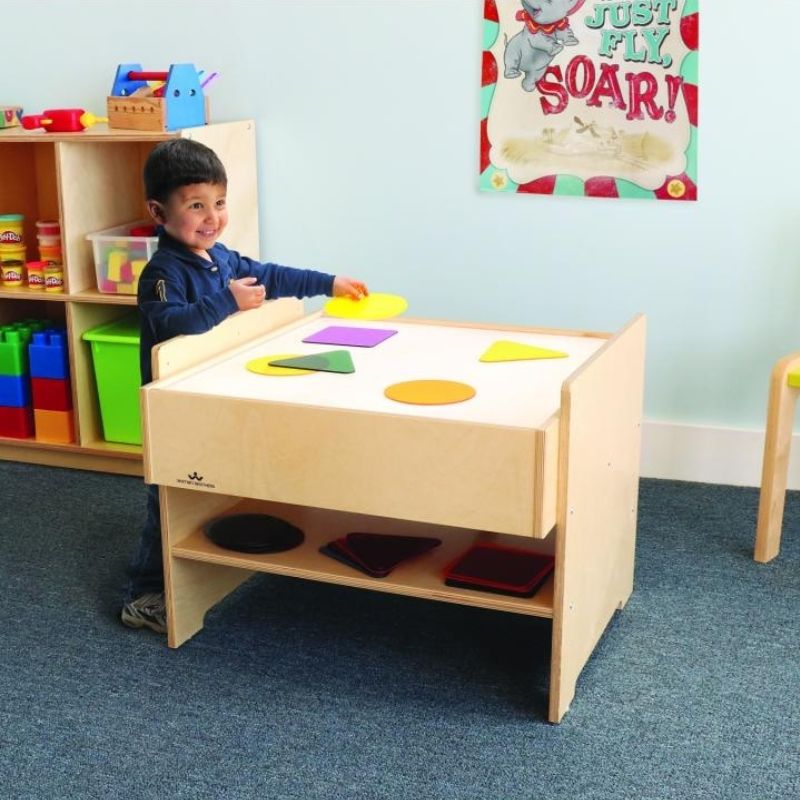 Child playing at the Whitney Brothers Superbright LED Light Table, using the illuminated surface to explore translucent materials on the adjustable-height sensory light table