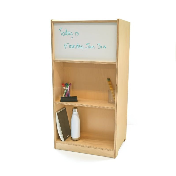 Whitney Brothers Cell Phone Locker WB1217 back panel with dry-erase board in use showing a classroom date message, with two open storage shelves below holding supplies and a water bottle
