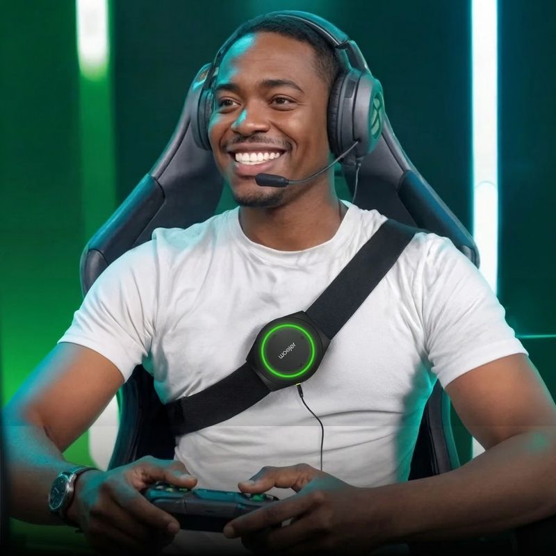 Gamer wearing the Woojer Strap 4 cross-body with a headset and controller, feeling game audio through this wearable haptic audio device