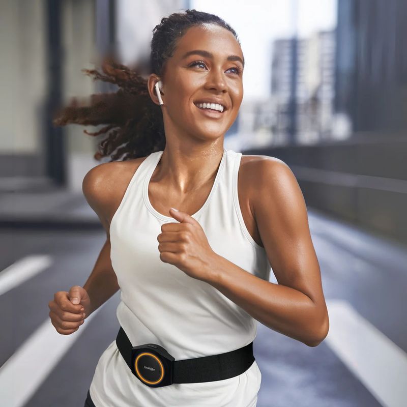 Runner wearing the Woojer Strap 4 at the waist with wireless earbuds, feeling the rhythm of her workout music through this portable haptic strap